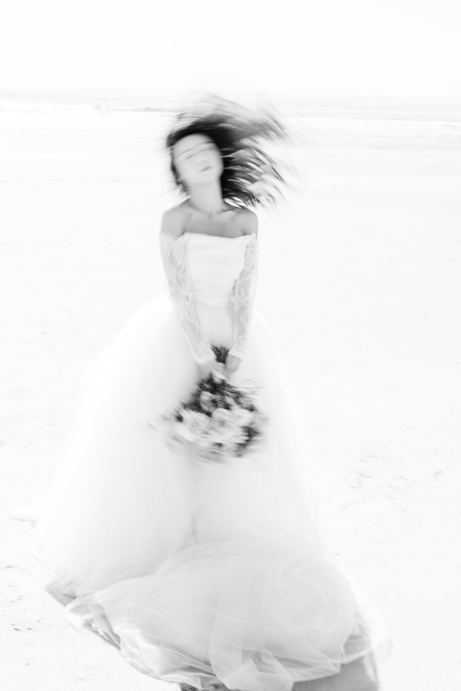 A bride in motion, bouquet in hand, photographed in black and white